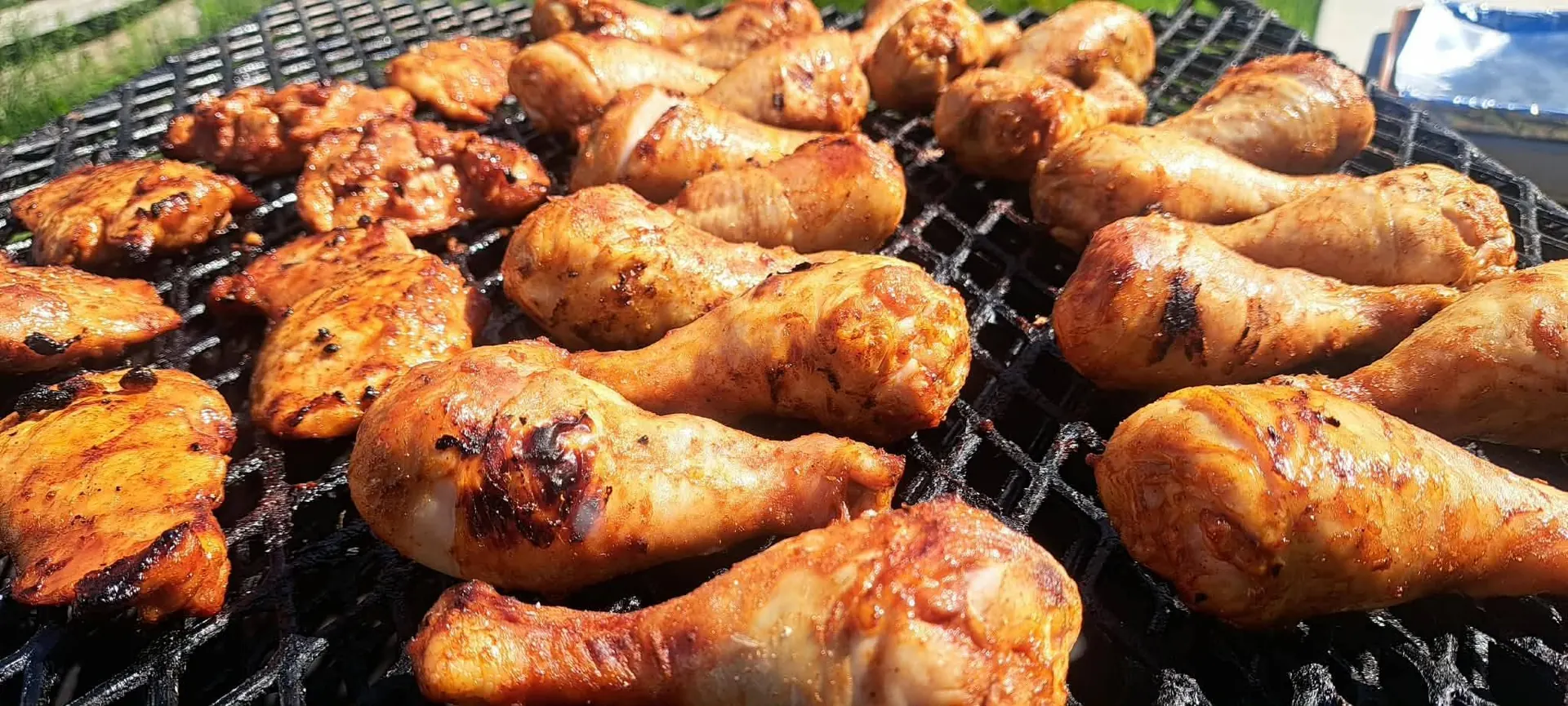 Chicken pieces grilling over open flame on the barbecue