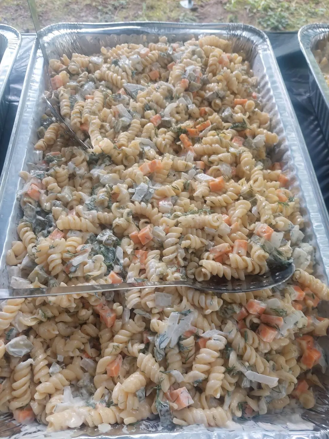 Buffet tray of creamy dill pickle pasta salad with serving spoons