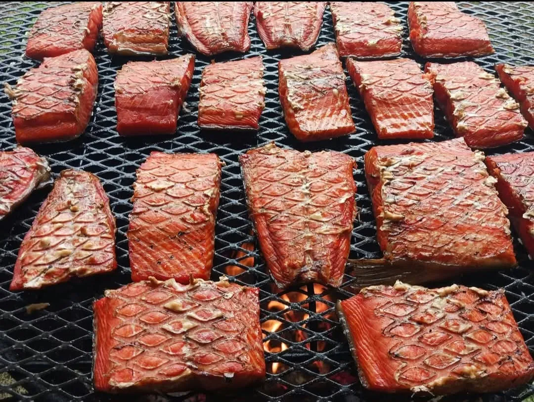 Wild salmon fillets scored and grilling on a wire rack over an open fire